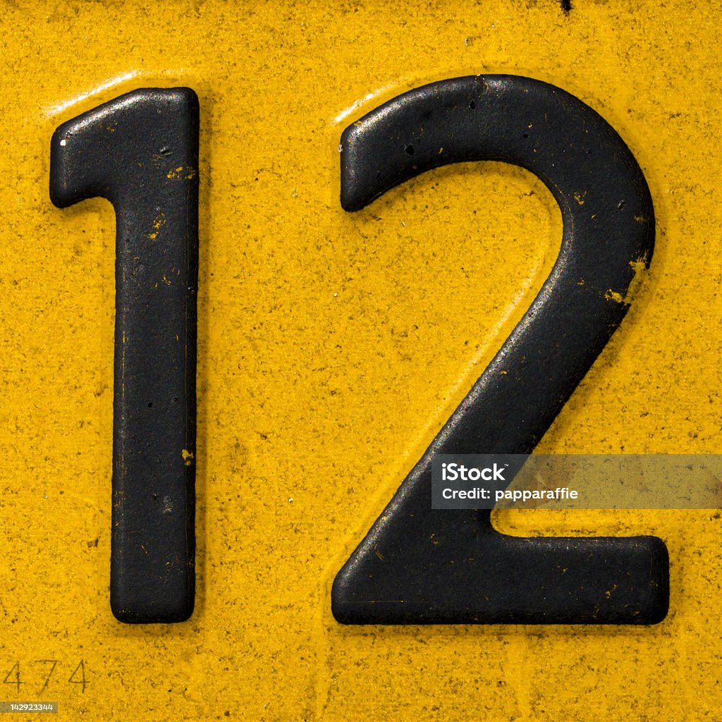 Closeup of a license plate with the number twelve number 12 on a dirty yellow plate Number 12 Stock Photo
