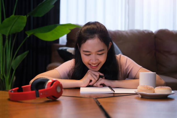 istock Pretty young woman doing homework while sitting in living room. 1429233768