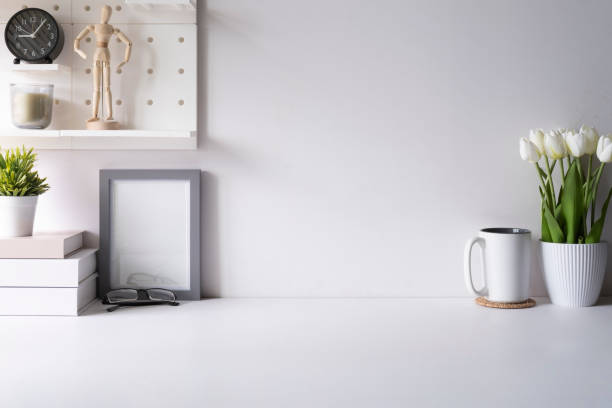 istock Bright modern workplace with flower pot, coffee cup, picture frame and books on white table. Copy space for your text. 1429233927