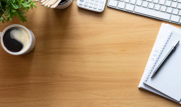 istock Simple workplace with wireless keyboard, notebook and coffee cup on wooden table. Top view with copy space for your text. 1429234580