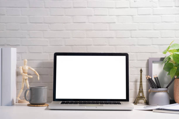 istock Front view laptop, coffee cup, notebook and houseplant on white table. Blank screen for your advertise text. 1429234856