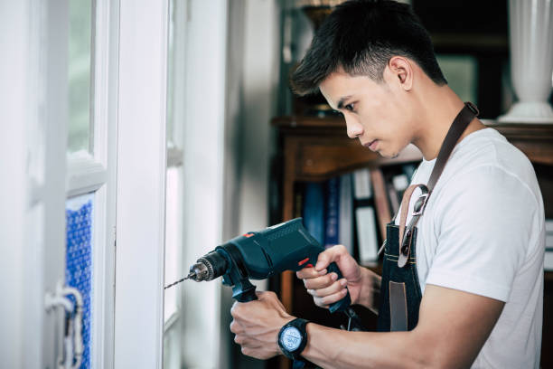 istock The carpenter holds the drill and drills the window. 1429235608