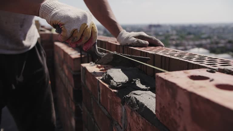 footage of bricklayer lays red brick, masonry wall