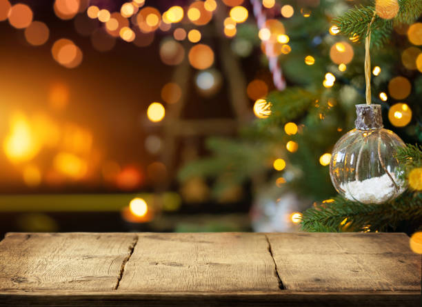 empty wooden table on christmas ornaments background with fireplace. copy space. - kerstmis stockfoto's en -beelden