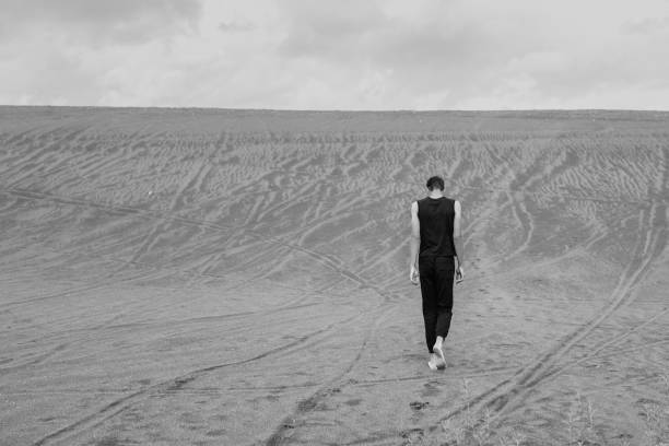 istock Young man walking alone on the sand in sandy desert 1429256773