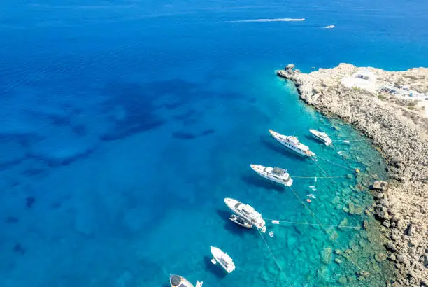 Drone aerial seascape with luxury yachts moored on the coast and unrecognised people swimming and relaxing. Summer vacations in the sea. Ayia Napa Cyprus