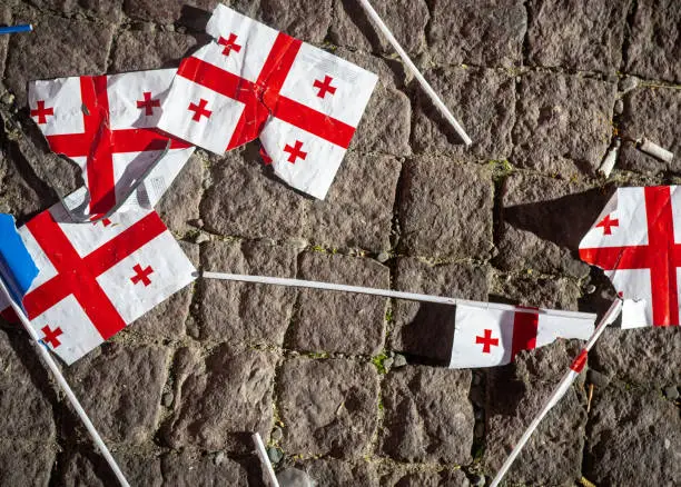 Photo of Many teared apart georgian flags on pavement. Crisis in caucasus concept. B&w background banner