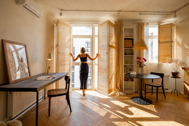mujer abre persianas de ventana en habitación soleada - window sun sunlight vertical fotografías e imágenes de stock