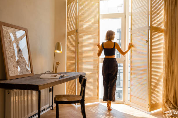 istock Woman opens window blinds at sunny room 1429269459