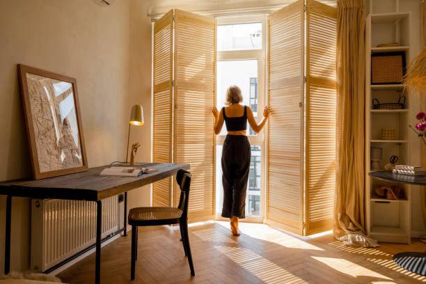 istock Woman opens window blinds at sunny room 1429269467