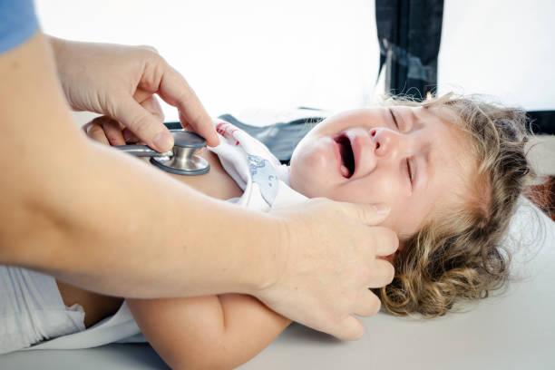 Pediatric doctor listening to a crying baby with a stethoscope stock photo