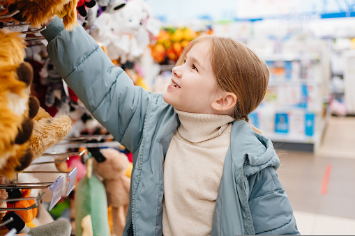 a happy little girl chooses a plush toy in a children's store. happy childhood. sale.