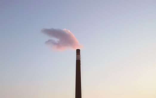A fluffy cloud aligns with a smokestack perfectly during sunset in Toronto, Ontario, Canada.