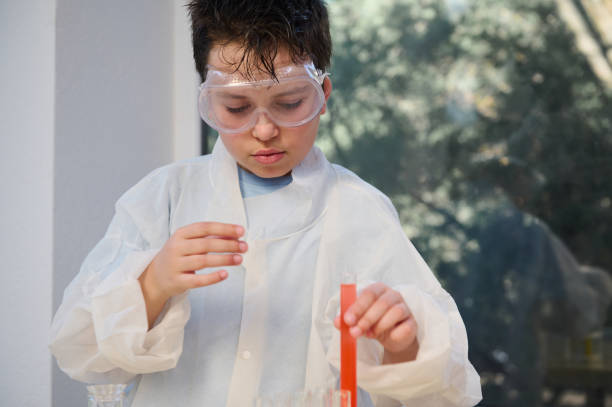 bonito caucasiano 10 anos de idade, experimentando com produtos químicos e soluções líquidas, durante uma aula de química. - 10 11 years elementary student student classroom - fotografias e filmes do acervo