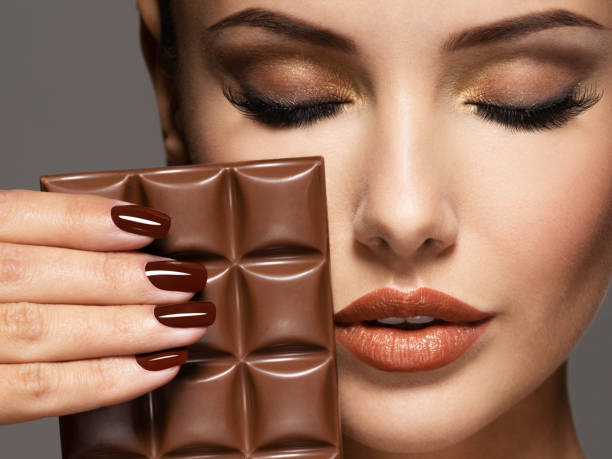 la belle femme avec des ongles bruns retient la barre du chocolat - brown chocolate candy bar close up photos et images de collection