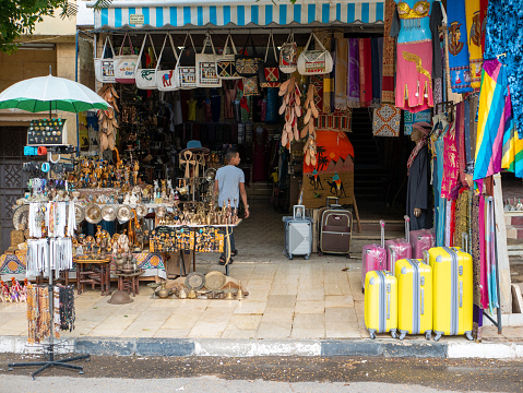 Cairo, Egypt - September 30, 2021: Cairo street with local tourist shops. Bright clothes in oriental style, souvenirs, bags and suitcases are sold near the store.