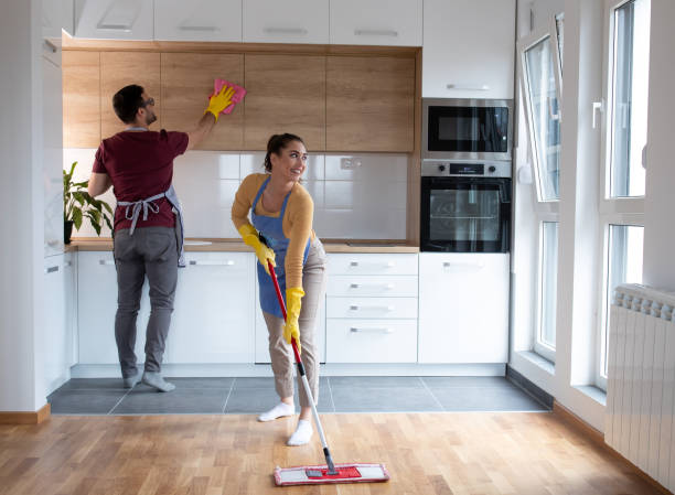 Couple doing chores together wiping dust and cleaning floor in their apartment. stock photo