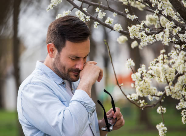 Man wiping nose because of pollen allergy in spring stock photo