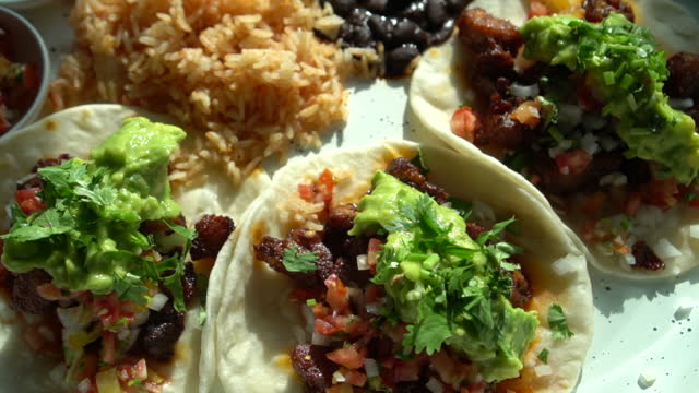 Mexican famous street food carnitas marinated pork taco plate with guacamole black bean lime and rice