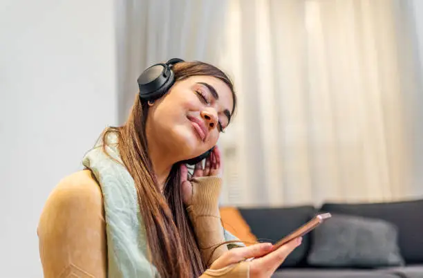 Calm brunette handsome woman, wearing headphones, towel around neck, listening to music.
