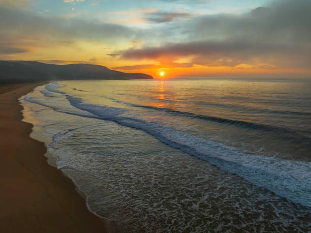 istock Peaceful sunrise over the ocean with small waves and clouds 1429302052