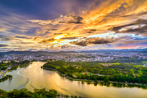 Aerial view of Da Lat city with sunset sky beautiful tourism destination in central highlands Vietnam. Urban development texture, green parks and city lake.