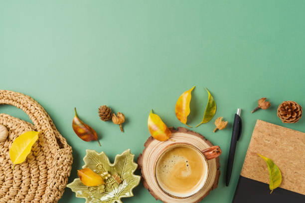 istock Coffeee cup, planner, bag and autumn leaves on green background. Stylish boho home office table. Top view, flat lay 1429305389
