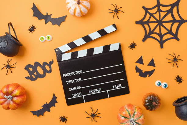 istock Movie clapper board and halloween decorations on orange background. Top view, flat lay 1429305465