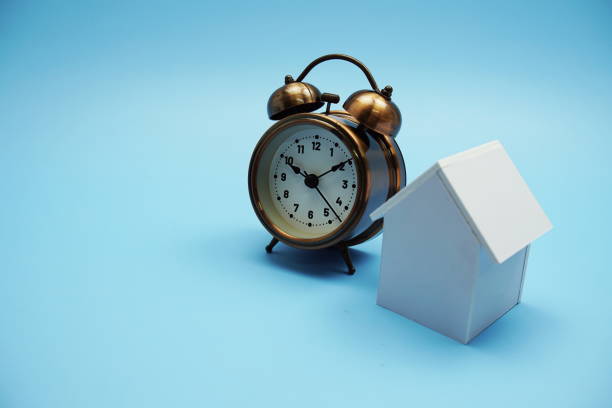 istock Alarm clock and house model with space copy on blue background 1429305584