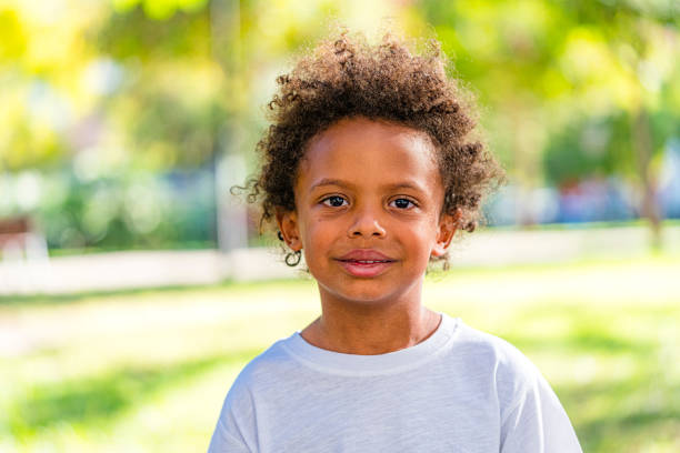 Portrait of five years old boy shot against defocused lush foliage background