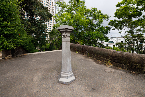 Old gray metal bollard with trees behind.