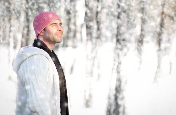 handsome young man standing in forest in the snow