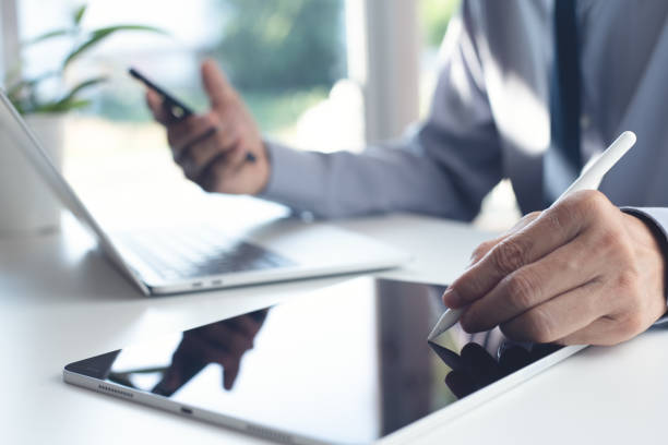 istock Businessman using stylus pen signing e-document on digital tablet during working on laptop computer and using mobile smartphone on office table 1429321593