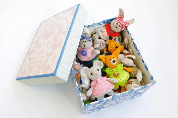Tiny crocheted toys in a decorative cardboard box on a white background