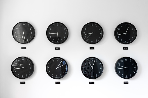Different times all around the world including Great Britain, Russia and Honk Kong. Eight clocks on wall showing world time zones.