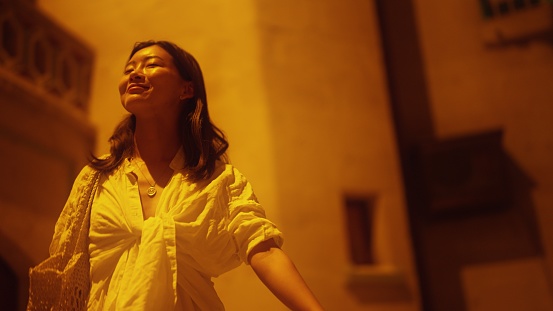 A portrait of a young woman in a small alley at night.