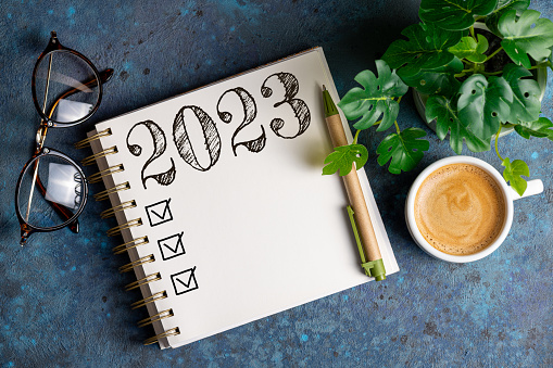 New year resolutions 2023 on desk. 2023 resolutions list with notebook, coffee cup on table. Goals, resolutions, plan, action, checklist concept. New Year 2023 template