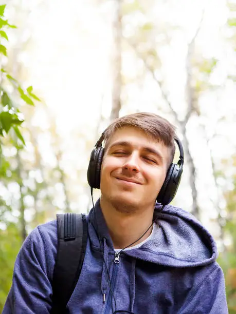 Happy Young Man in Headphones listen to the Music outdoor