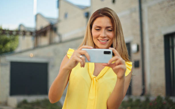 istock Beautiful woman taking pictures with her smartphone while exploring a city 1429346734