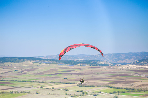 Sopot, Bulgaria - June 16, 2019: Young woman gliding in the sky above the town of Sopot, Bulgaria. Paragliding jump from the hills of Stara Planina Mountain.