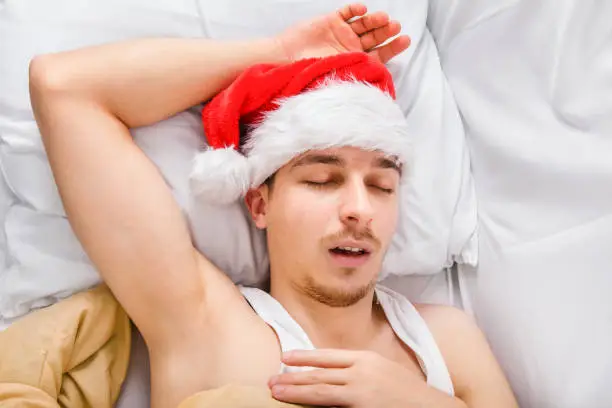 Man in Santa Hat sleeping in the Bed at the Home