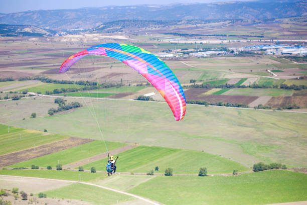 jeune homme volant avec un parapente coloré. sport extrême - action adventure aerospace industry air vehicle photos et images de collection