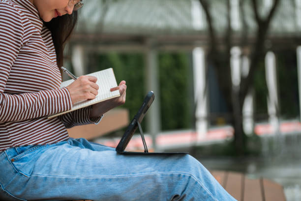 istock Close-up Adult student writing note on a book at park. 1429350230