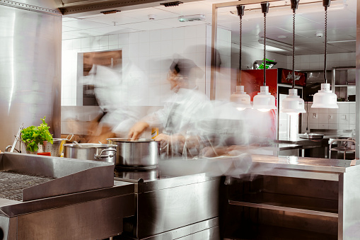Long exposure with motion blurred chefs at work in professional kitchen