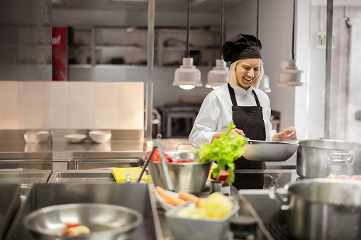 Female chef in a restaurant or hotel kitchen cooking delicious food
