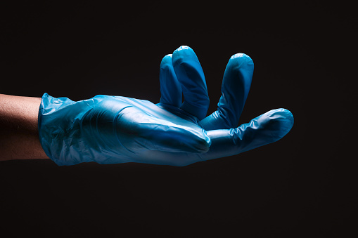 Man's hand wearing nitrile gloves on black background