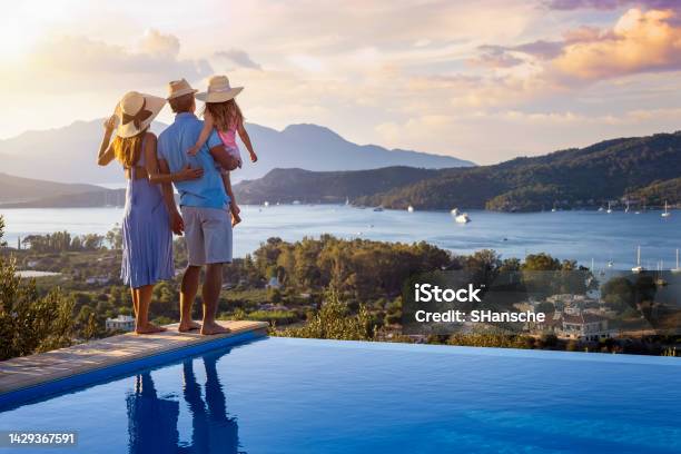 A Family On Summer Holidays Stands By The Swimming Pool And Enjoys The Beautiful Sunset Stock Photo - Download Image Now