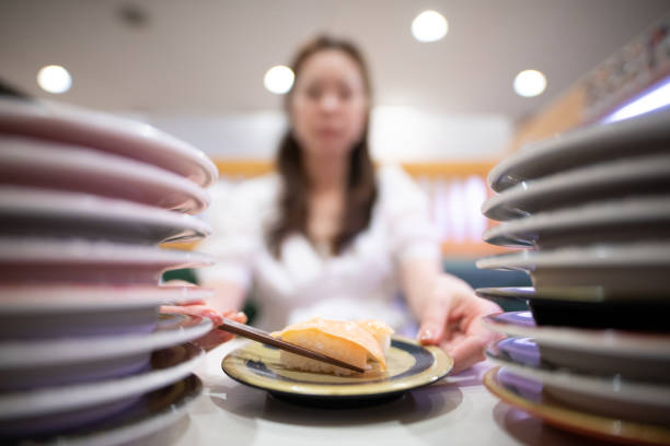 Woman eating salmon sushi with chopsticks