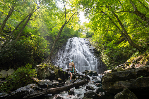 Woman hiking in in the forest on summer vacation trip. Crabtree Falls just off the Blue Ridge Parkway. Blue Ridge Mountains, North Carolina, USA.
