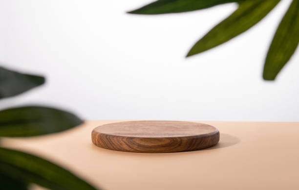 istock Empty podium with a palm leaf. A round wooden stage on a beige table. 1429383469